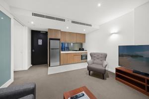 a living room with a chair and a television at Flinders Street Apartments in Melbourne