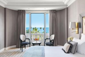 a hotel room with a bed and a view of the ocean at Hôtel Barrière Le Majestic Cannes in Cannes