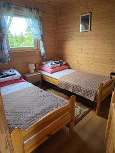 - 2 lits dans une cabane en rondins avec fenêtre dans l'établissement Domki U Julka Nad Jeziorem Solińskim z Jacuzzi, à Werlas