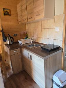 Elle comprend une petite cuisine avec un évier et des placards en bois. dans l'établissement Domki U Julka Nad Jeziorem Solińskim z Jacuzzi, à Werlas