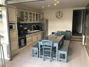 a kitchen with a table and blue chairs in it at L'Entre Vagues in Saint-Jean-de-Monts