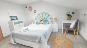 a white bedroom with a bed and a chair at El ático azul in Tordesillas