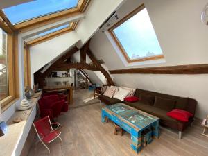 ein Wohnzimmer im Dachgeschoss mit einem Sofa und einem Tisch in der Unterkunft L'académie de Clémence, Guest House Paris-Roland-Garros in Boulogne-Billancourt