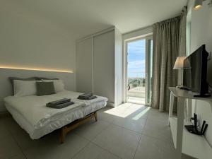 een slaapkamer met een bed en een glazen schuifdeur bij Feelgood Homestay Sagres in Sagres