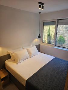 - une chambre avec un lit doté de draps et d'oreillers blancs dans l'établissement Anja & Ogo Apartment sea View & Pool, à Petrovac na Moru