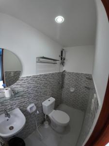 a bathroom with a white toilet and a sink at La Salangane Beach Hotel - Downtown in El Nido