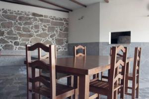 a wooden table and chairs in a room with a stone wall at Casa na Aldeia in Arcos de Valdevez