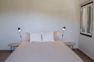 a bedroom with a large white bed with two tables at Casa na Aldeia in Arcos de Valdevez