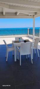 einen weißen Tisch und Stühle auf einer Terrasse mit Meerblick in der Unterkunft Attico Tra Cielo e Mare in Margherita di Savoia