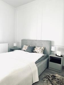 a bedroom with a large white bed with a night stand at Małe Garbary 8 Apartment in Poznań