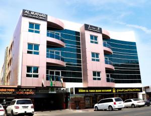 un grande edificio con macchine parcheggiate di fronte di Al Manar Hotel Apartments a Dubai