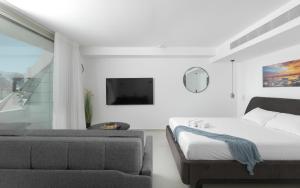 a white bedroom with a bed and a couch at סוויטות עם נוף וצמודות לים במתחם SeaSide היוקרתי עם בריכה - By SEAELO EILAT in Eilat