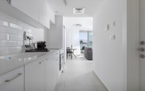 a white kitchen with a sink and a table at סוויטות עם נוף וצמודות לים במתחם SeaSide היוקרתי עם בריכה - By SEAELO EILAT in Eilat