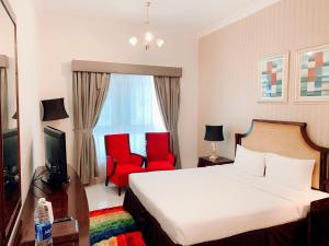 a hotel room with a bed and two red chairs at Al Manar Hotel Apartments in Dubai