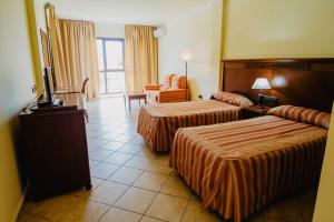 a hotel room with two beds and a television at Hotel Hacienda Don Manuel in Granja de Torrehermosa