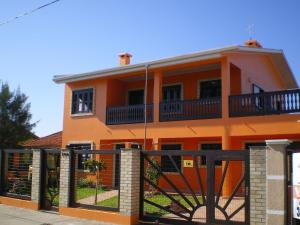 an orange house with a black fence in front of it at Casa Oasis Sul Tramandaí in Tramandaí