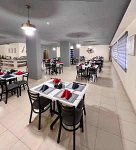 Sky Hotel في العقبة: غرفة طعام مع طاولات وكراسي بمناديل حمراء