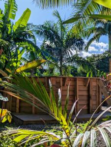 a wooden bench in a garden with palm trees at Villa a la Possession in La Possession +2 photos