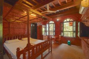 - une chambre avec un lit en bois et des fenêtres dans l'établissement Konkan Nest Resort, à Ganpatipule
