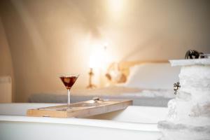 Una copa de vino en una bandeja junto a una cama en Baita Naturas con piscina idromassaggio calda, privata e gratuita, en Rossana