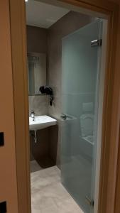 baño con lavabo y puerta de ducha acristalada en Rittson - Boutique Hotel en Vlorë