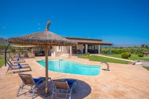 einen Pool mit Stühlen und einem Strohschirm in der Unterkunft Villa Coira in Alcúdia