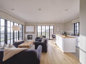 a living room with couches and a kitchen at Reetland am Meer - LuxusPlus Reetdachvilla mit 4 Schlafzimmern, Außensauna, Loungebereich und Kamin G07 in Dranske