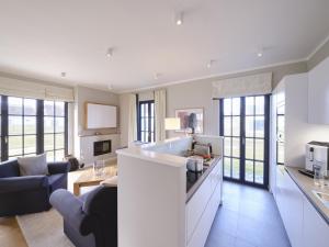 a kitchen and living room with a couch and a table at Reetland am Meer - Luxus Reetdachvilla mit 3 Schlafzimmern, Sauna und Kamin G05 in Dranske