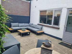 patio con sofá, mesas y ventana en Tip! Noordwijk city center house en Noordwijk aan Zee