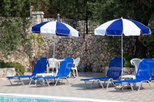 um grupo de cadeiras e guarda-sóis ao lado de uma piscina em Crystal Blue Hotel by Konnect, Barbati em Barbati