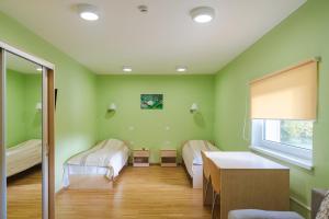 a green room with two beds and a table at Alutaguse Tervisespordikeskuse Päikesemaja in Vasavere