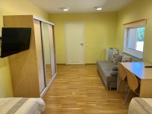 a living room with a couch and a tv in a room at Alutaguse Tervisespordikeskuse Päikesemaja in Vasavere