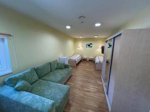 a living room with a green couch and a bedroom at Alutaguse Tervisespordikeskuse Päikesemaja in Vasavere