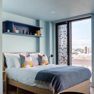 una camera da letto con un grande letto con una grande finestra di Coleman Court Summer Apartments a Cork