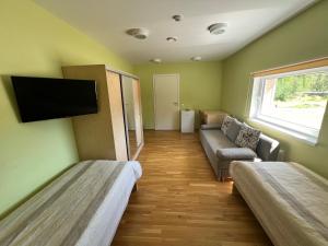 a room with two beds and a couch and a flat screen tv at Alutaguse Tervisespordikeskuse Päikesemaja in Vasavere