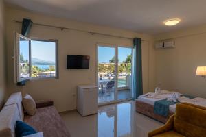 a room with a bed and a tv and a couch at Golden Hotel in Ksamil