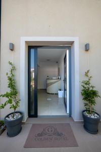 a door to a building with two potted plants at Golden Hotel in Ksamil