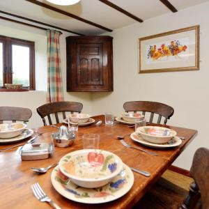 a wooden table with plates and utensils on it at Llynhillyn Cottage in Presteigne +22 photos