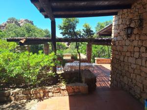 a patio of a house with a stone wall at Villa La Lecceta surrounded by greenery and sea view with sunset in Costa Paradiso +38 photos