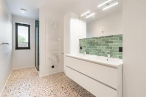 un bagno bianco con lavandino e doccia di Paradisio II a Oostduinkerke