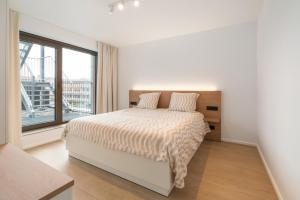 una camera bianca con un letto e una grande finestra di Paradisio II a Oostduinkerke
