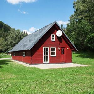 什平德萊魯夫姆林的住宿－Chalets & Apartments - Base Camp Medvědín，绿色田野上带黑色屋顶的红色谷仓