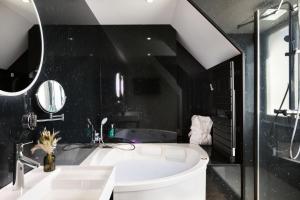baño con bañera blanca y pared negra en Hôtel & Spa Le Maury, Vannes, The Originals Boutique en Vannes