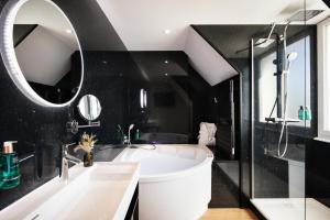 y baño con bañera blanca y espejo. en Hôtel & Spa Le Maury, Vannes, The Originals Boutique en Vannes
