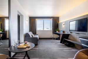 トゥールーズにあるNemea Appart Hotel Concorde Toulouse Gare Matabiauの大型テレビとリビングルームが備わるホテルルームです。