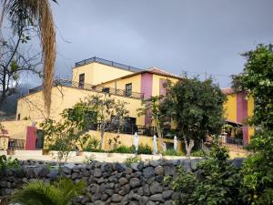 Casa amarilla y rosa con pared de piedra en Hotel Rural La Raya 1866, en Güímar