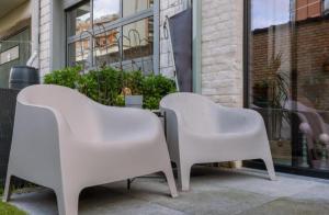 twee witte stoelen voor een gebouw bij loftlivinq@sea in Middelkerke
