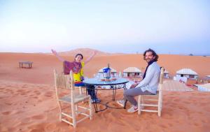 Ein Mann und eine Frau sitzen an einem Tisch in der Wüste. in der Unterkunft RiadSuerteloca Merzouga in Merzouga