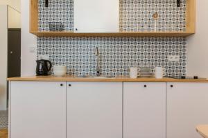 uma cozinha com armários brancos e uma parede de azulejos em 19Rooms em Cracóvia