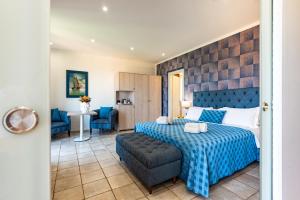 een slaapkamer met een blauw bed en een bank bij Hotel Baia Del Capitano in Cefalù